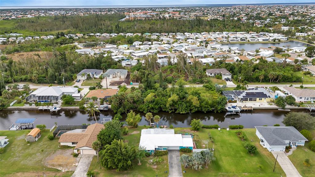 An aerial view shows waterfront houses with docks along a canal in a residential neighborhood — 3410, 3402, 3420 COLONY COURT, PUNTA GORDA, FL