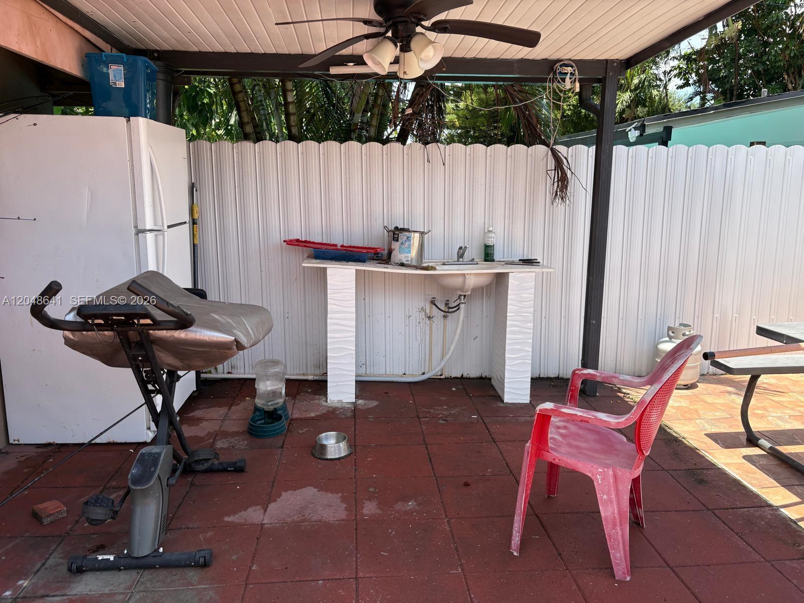 An outdoor patio area features a sink, a refrigerator, an exercise bike, and a chair — 6444 Fletcher St, Hollywood FL 33023, HOLLYWOOD, FL