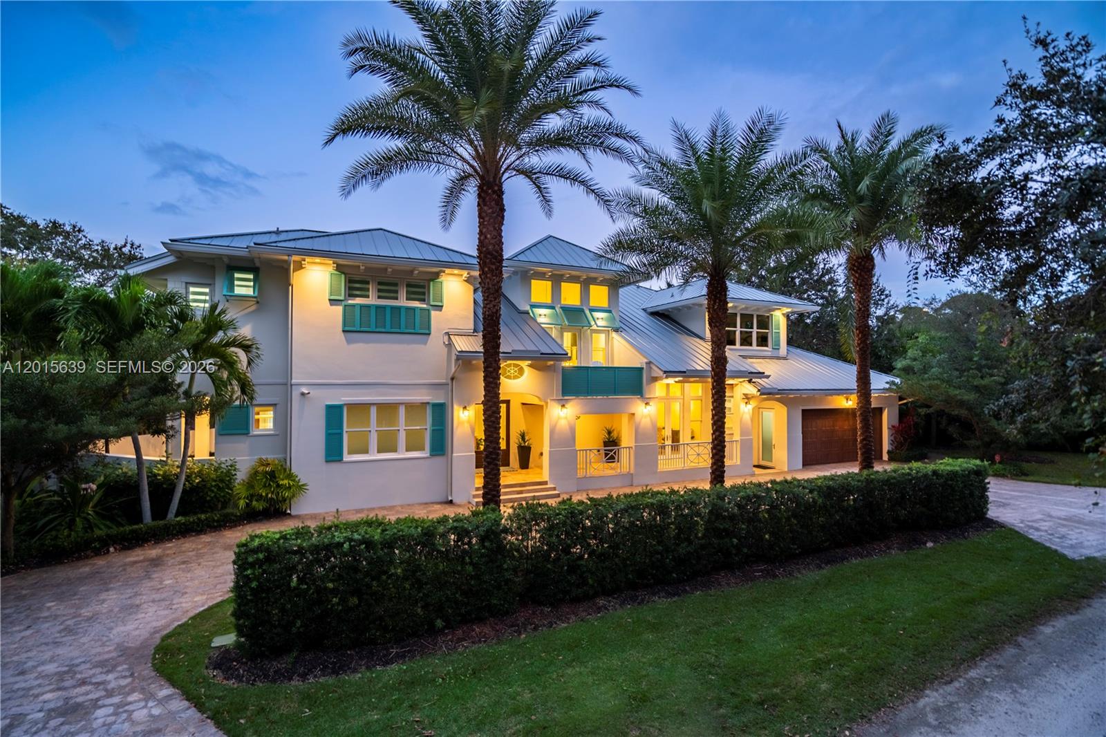 A two-story house with a metal roof, teal shutters, and palm trees at dusk — 545 SW Indianola St, Stuart FL 34994, STUART, FL