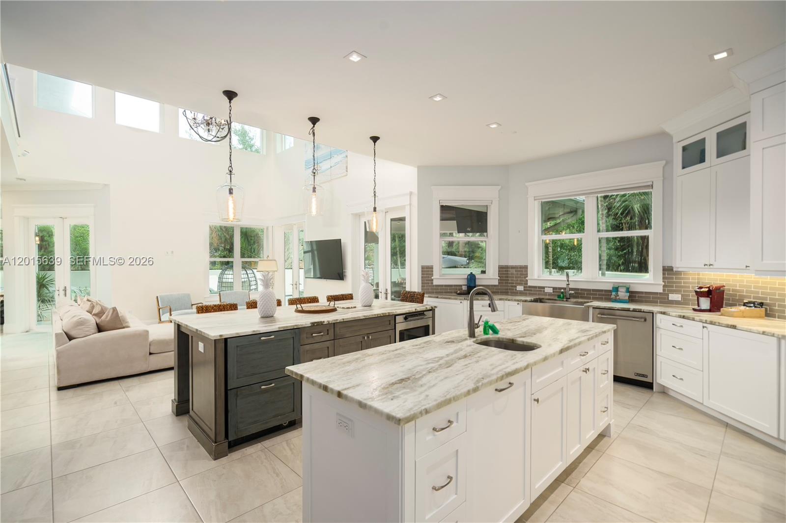 A bright, open-concept kitchen features two large islands, white cabinetry, and marble countertops — 545 SW Indianola St, Stuart FL 34994, STUART, FL