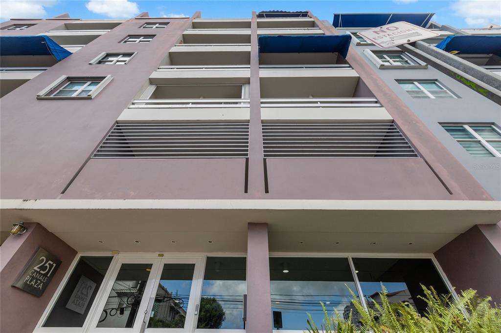 A low-angle exterior view of a multi-story building with balconies and a glass-fronted entrance — 251 CANALS STREET UNIT 401, SANTURCE, PR