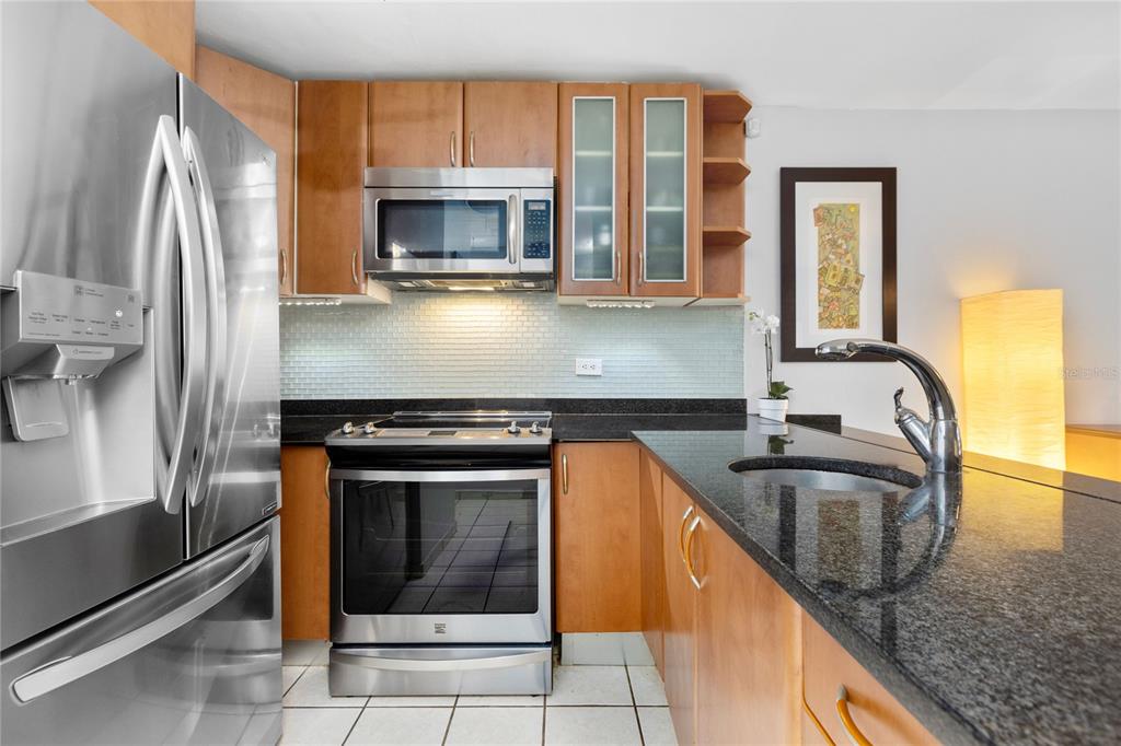 A kitchen features stainless steel appliances, wood cabinetry, and a dark granite countertop with a sink — 251 CANALS STREET UNIT 401, SANTURCE, PR