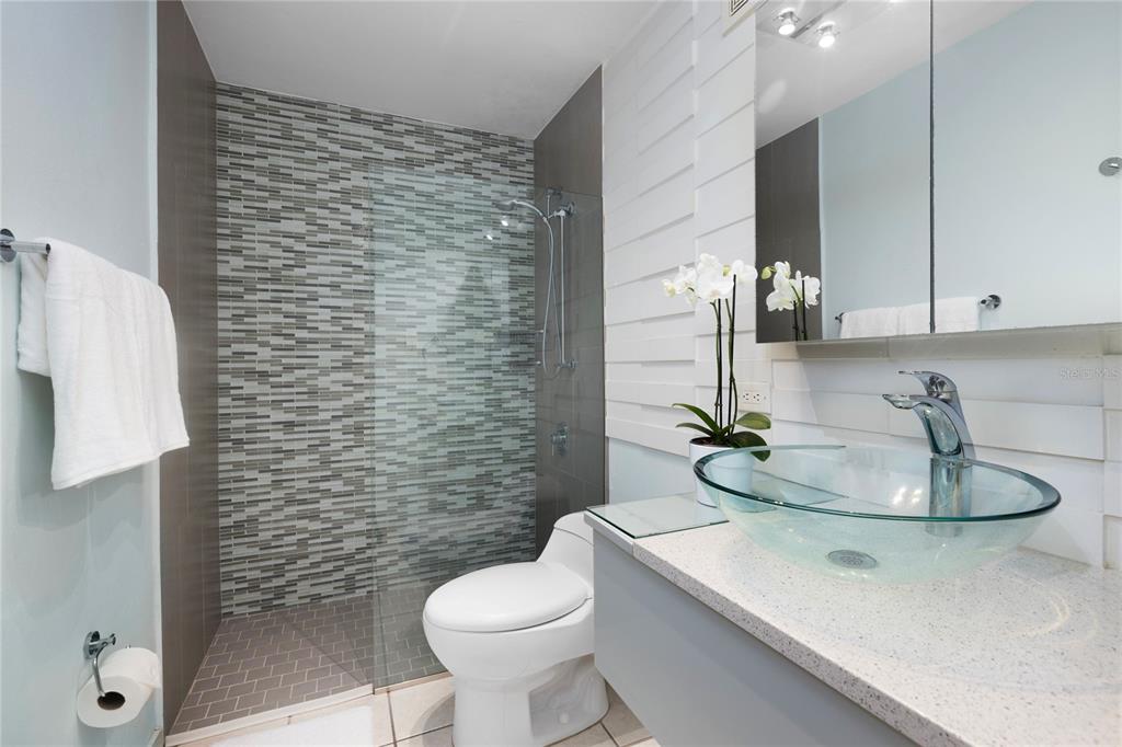 A modern bathroom features a glass vessel sink, a walk-in shower, and gray tiled walls — 251 CANALS STREET UNIT 401, SANTURCE, PR