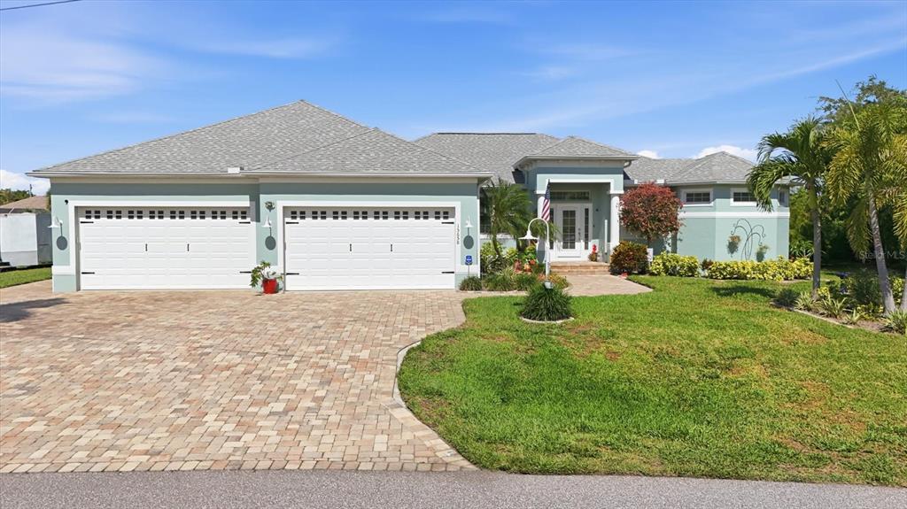 A single-story house with a light green exterior, a three-car garage, and a paved driveway — 15658 APPLEWHITE CIRCLE, PORT CHARLOTTE, FL