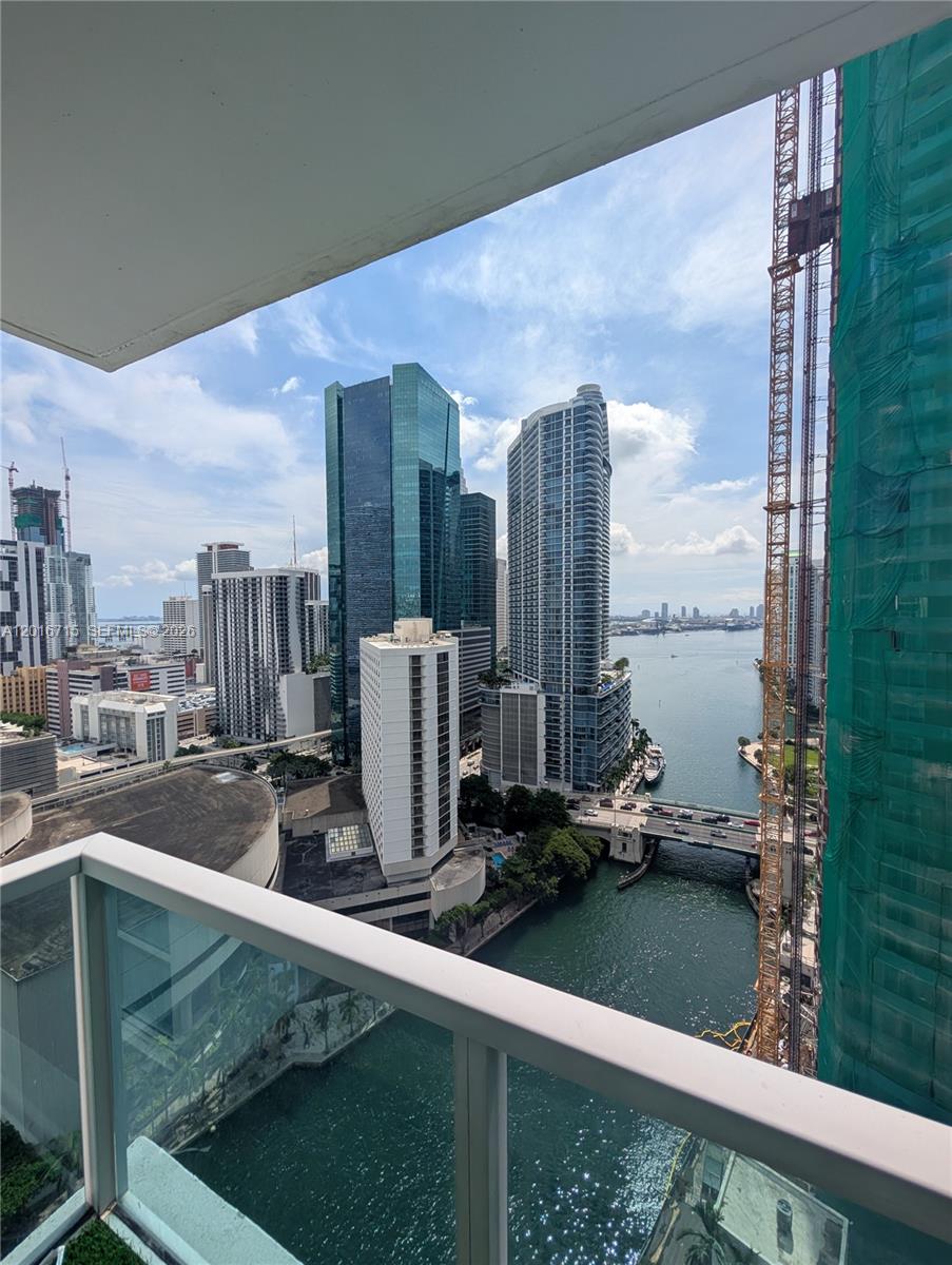 A balcony view overlooks a river, city skyscrapers, and a construction crane in Miami — 31 SE 5th St # 3002, Miami FL 33131, MIAMI, FL