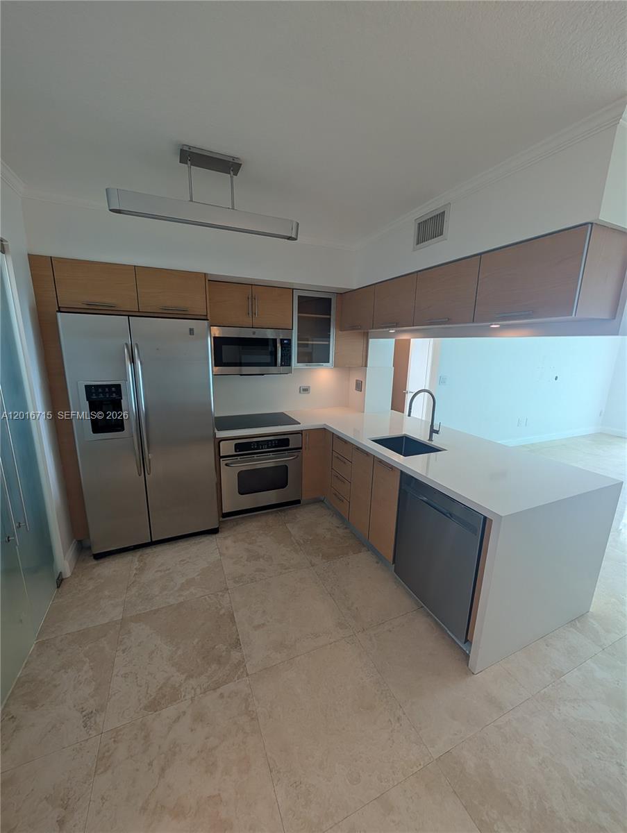 A modern kitchen features stainless steel appliances, light wood cabinetry, and white countertops — 31 SE 5th St # 3002, Miami FL 33131, MIAMI, FL