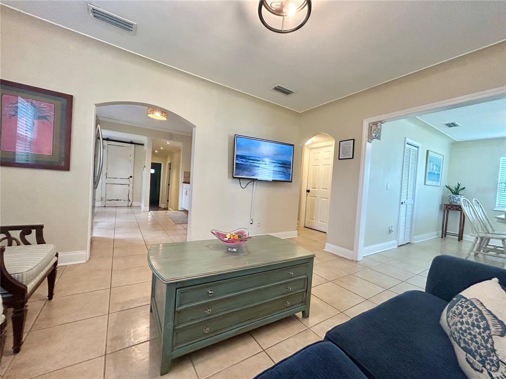 A living room features tile flooring, a blue sofa, a coffee table, and a wall-mounted television — 5618 20TH AVENUE S, GULFPORT, FL