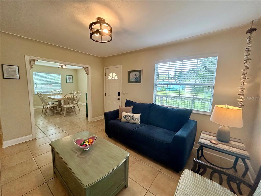 A living room with a blue sofa, tile floors, and an adjacent dining area — 5618 20TH AVENUE S, GULFPORT, FL