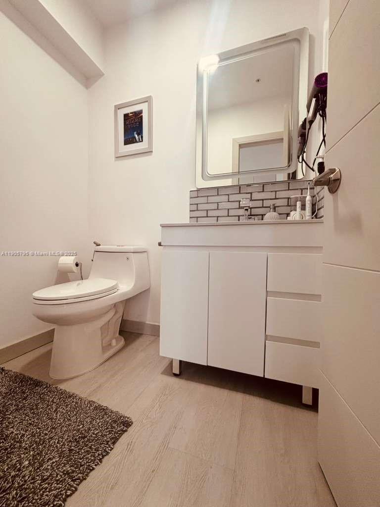 A bathroom features a white vanity, a toilet, a framed picture, and a wall mirror — 2829 Indian Creek Dr # 1403, Miami Beach FL 33140, MIAMI BEACH, FL