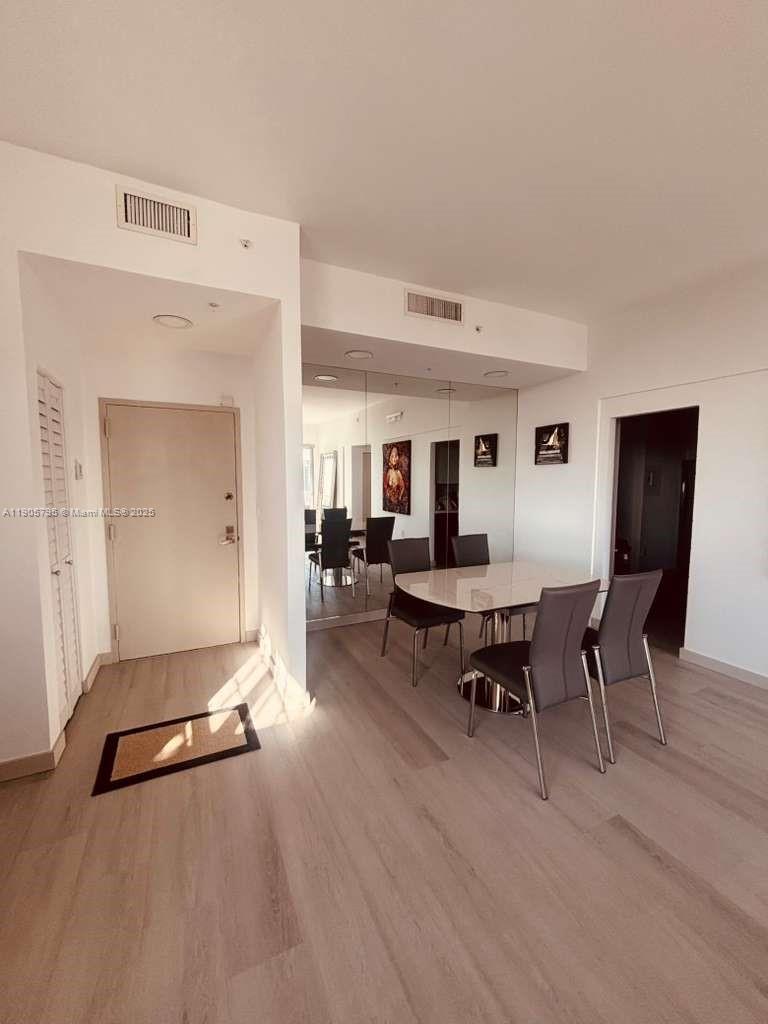 A dining area features a glass table, four chairs, and a large mirrored wall — 2829 Indian Creek Dr # 1403, Miami Beach FL 33140, MIAMI BEACH, FL
