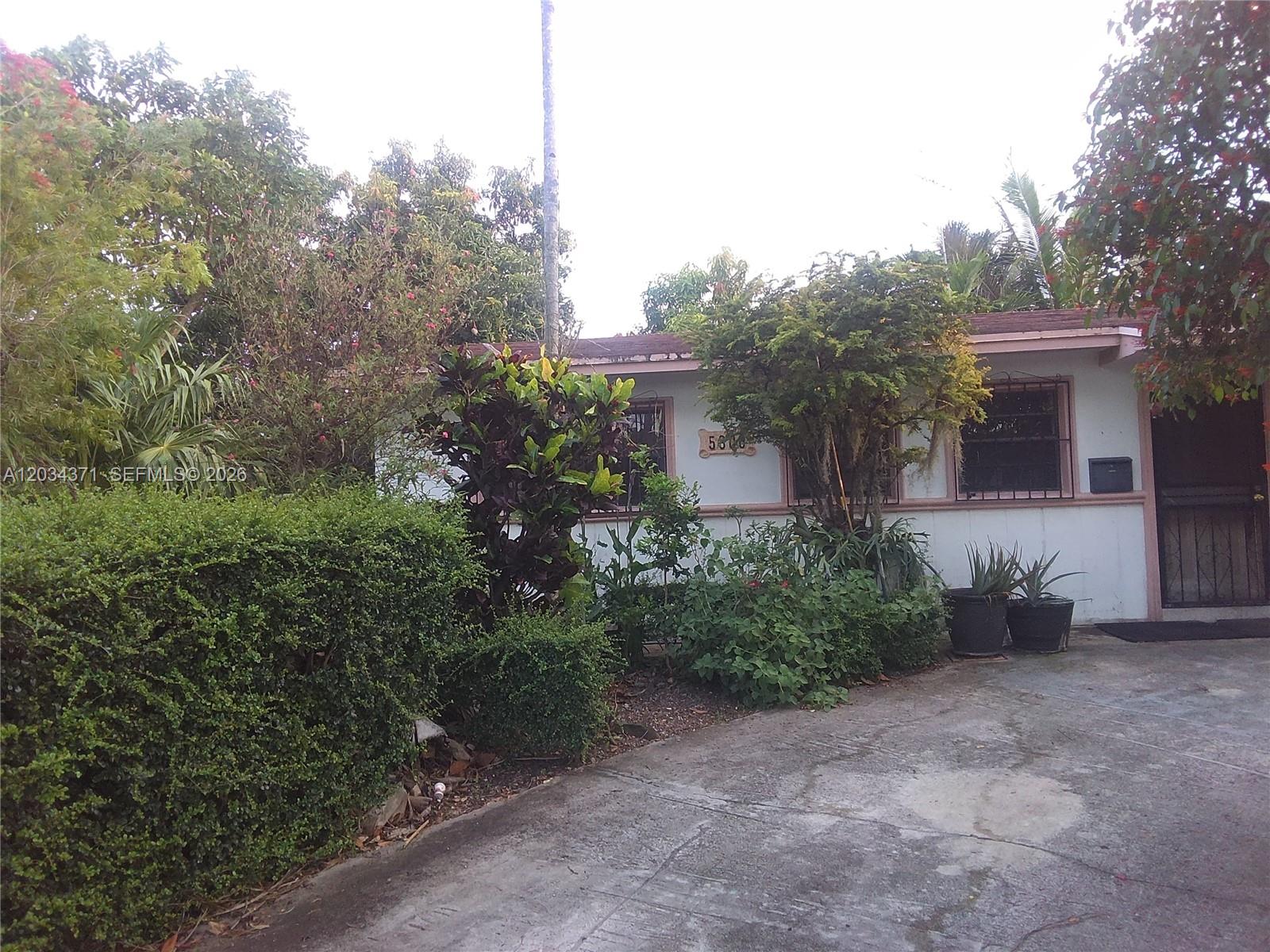 A single-story house with white siding, a concrete driveway, and lush landscaping in the front — 5300 SW 103rd Pl, Miami FL 33165, MIAMI, FL