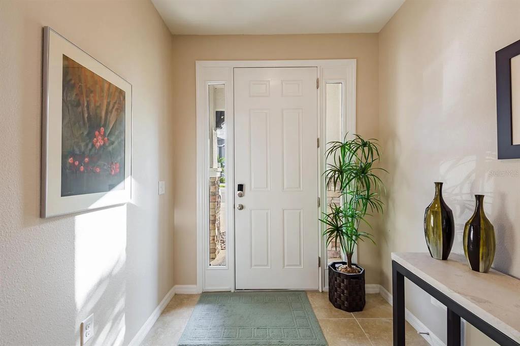 A bright entryway features a white front door with sidelights, tile flooring, and a console table — 8688 ICE WINE STREET, SARASOTA, FL