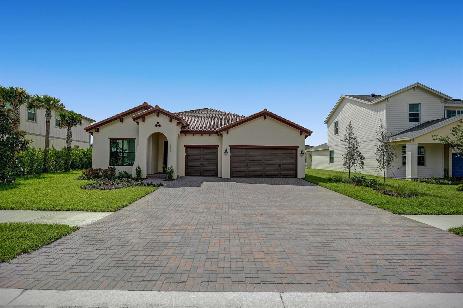 A single-story house with a tiled roof, brown garage doors, and a paved driveway — 19411 Broad Shore Walk, FL 33470, FL