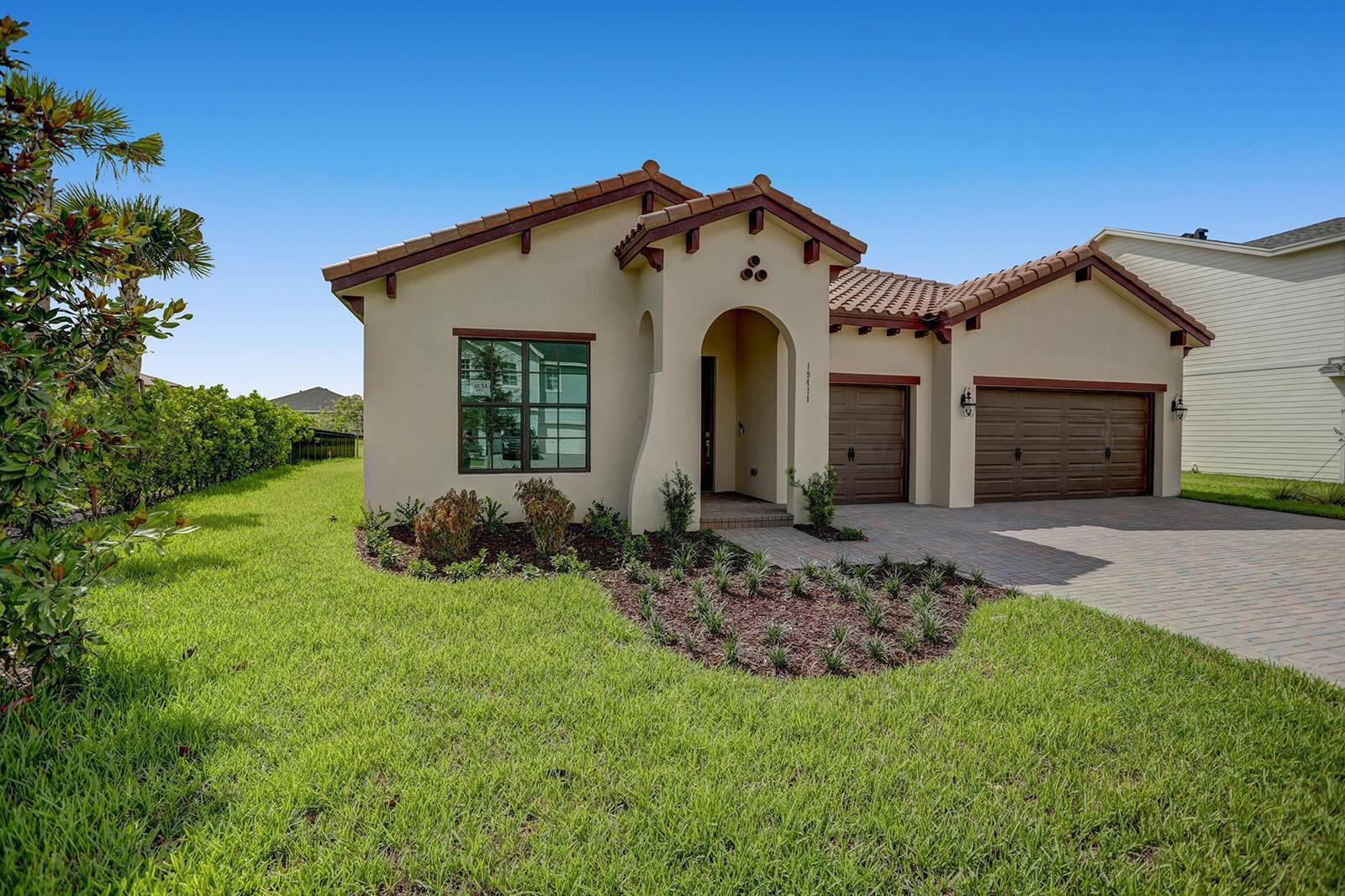A single-story stucco house with a tile roof, arched entryway, and a three-car garage — 19411 Broad Shore Walk, FL 33470, FL