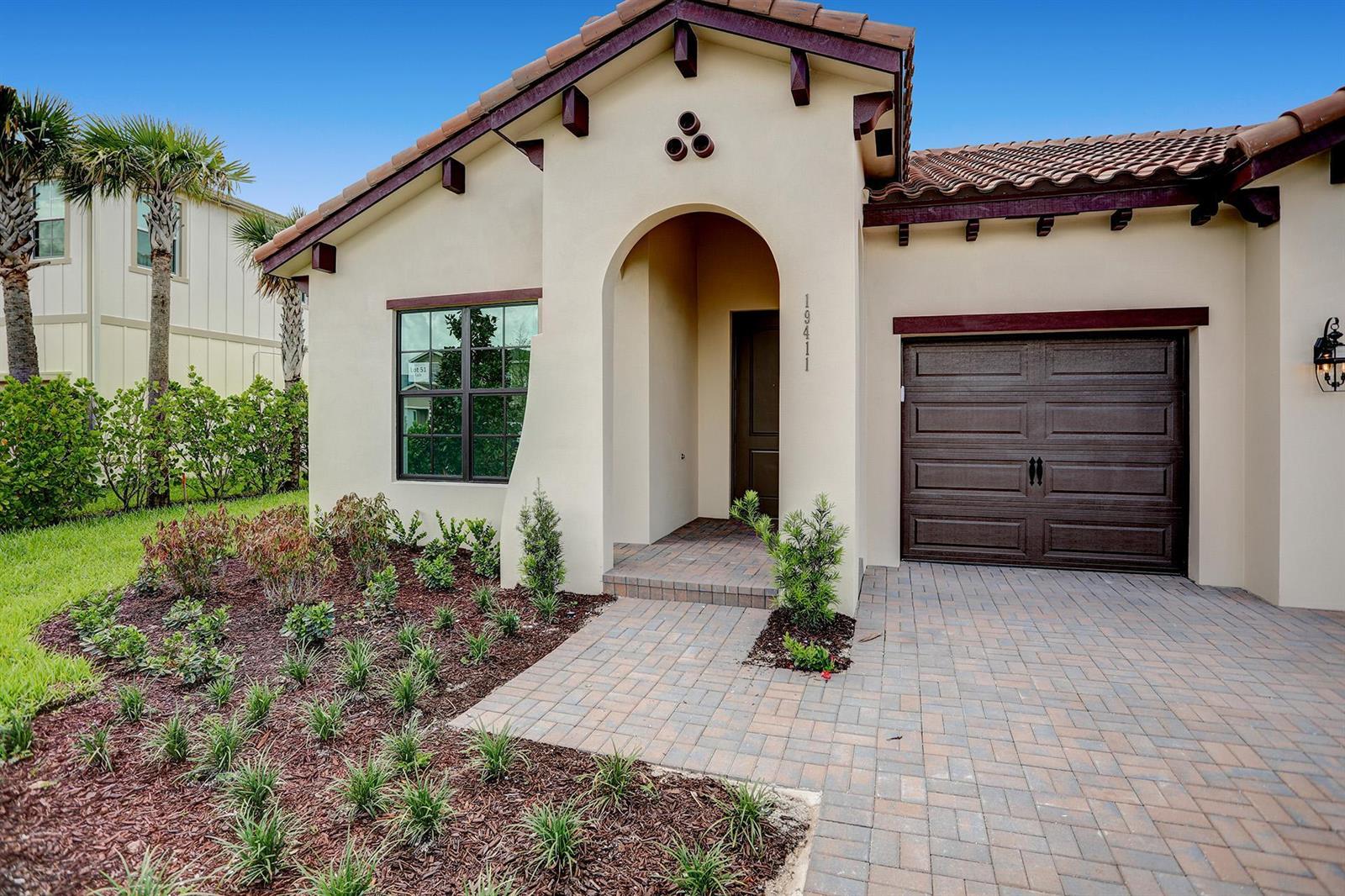 A single-story stucco house with a tiled roof, arched entryway, and a paved driveway — 19411 Broad Shore Walk, FL 33470, FL