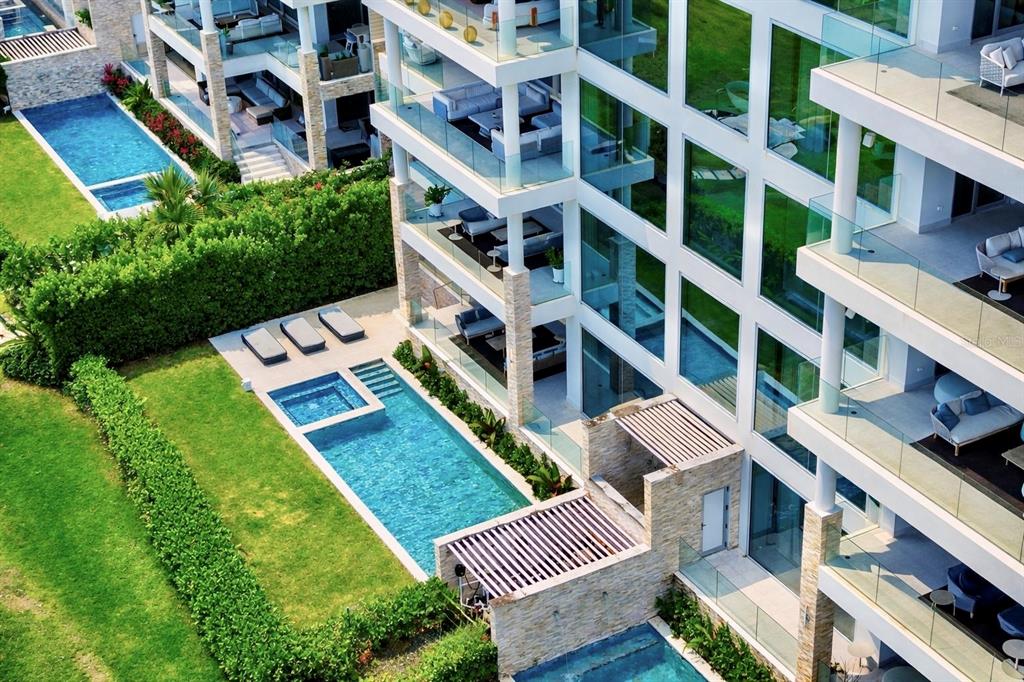 An aerial view shows a multi-story apartment building with private balconies and ground-level swimming pools — 3101 OCEAN DRIVE, RIO GRANDE, PR