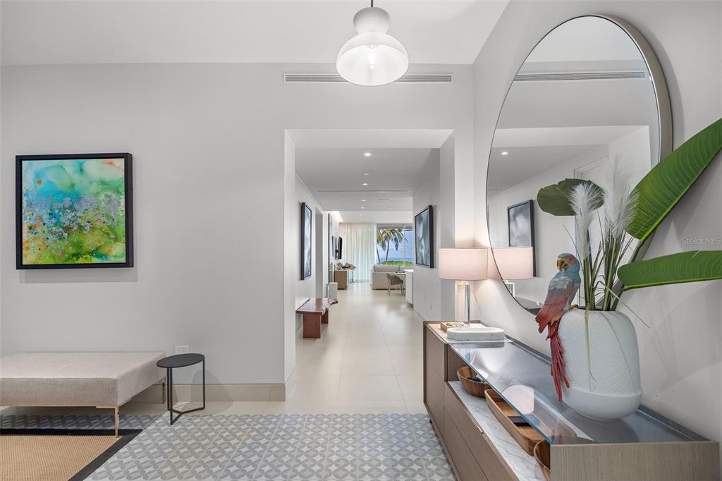 A modern entryway features a large round mirror, a console table, and a hallway view — 3101 OCEAN DRIVE, RIO GRANDE, PR