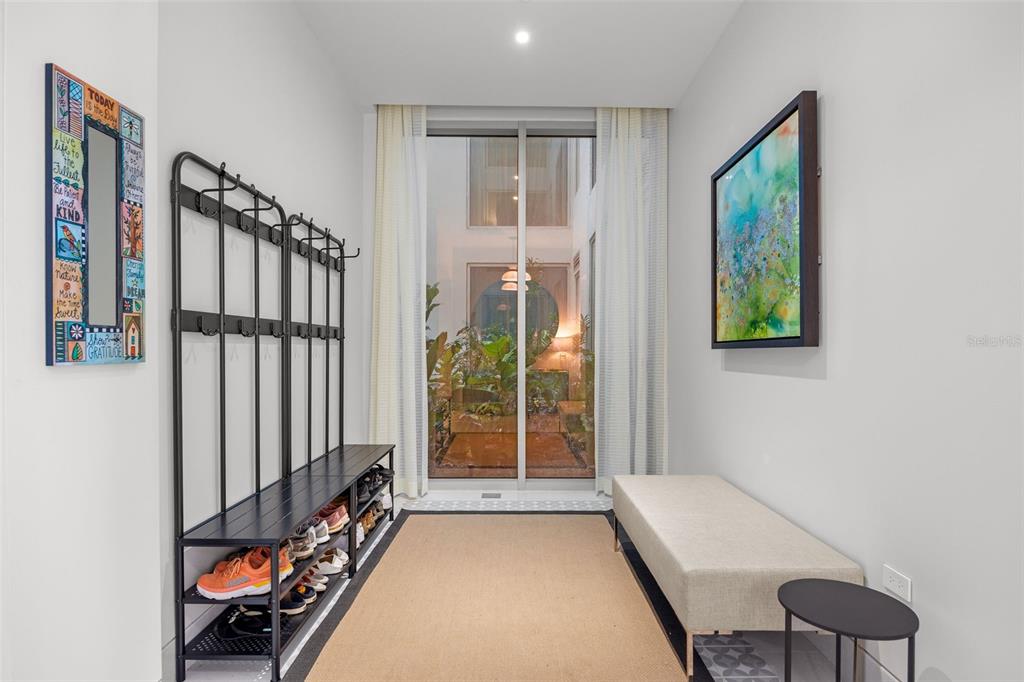 A modern entryway features a shoe rack, a bench, and a view of an interior courtyard — 3101 OCEAN DRIVE, RIO GRANDE, PR