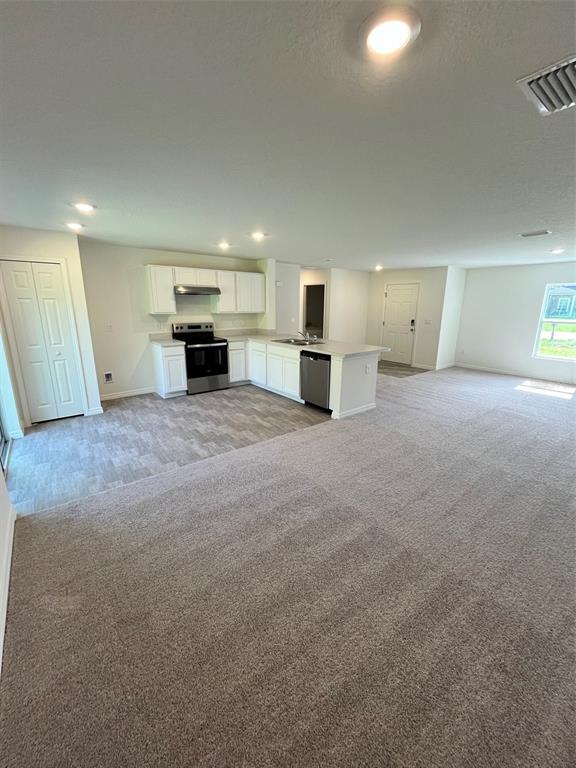 An open-concept kitchen features white cabinets, stainless steel appliances, and a central island — 10115 MCMAHON AVENUE, HASTINGS, FL