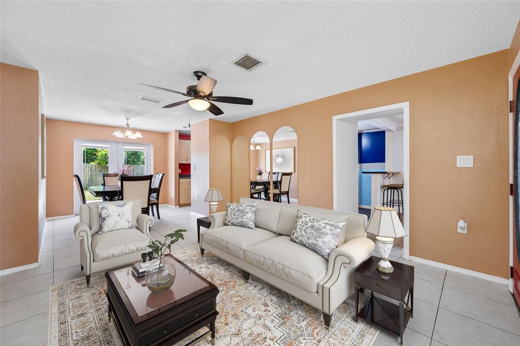 A living room with beige walls, tile flooring, a sofa, an armchair, and a dining area — 3748 15TH AVENUE SE, LARGO, FL