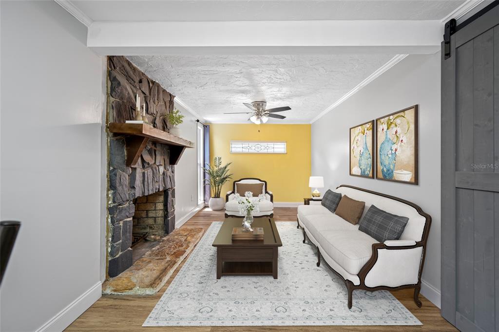 A living room features a stone fireplace, a white sofa, and a yellow accent wall — 3748 15TH AVENUE SE, LARGO, FL