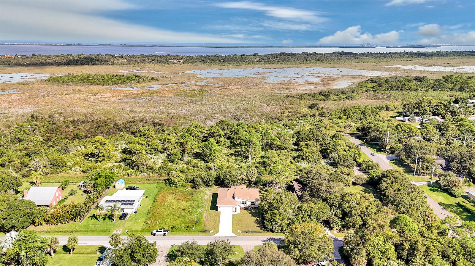 An aerial view shows a house with a driveway surrounded by trees and wetlands — 5310 Sunset Boulevard, Fort Pierce FL 34982, FORT PIERCE, FL