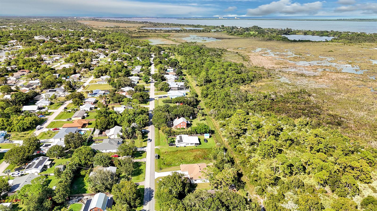 An aerial view shows a residential street bordered by dense woods and a large marsh — 5310 Sunset Boulevard, Fort Pierce FL 34982, FORT PIERCE, FL