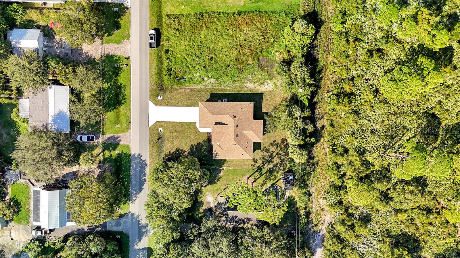An aerial view shows a single-family home with a driveway, yard, and surrounding wooded area — 5310 Sunset Boulevard, Fort Pierce FL 34982, FORT PIERCE, FL