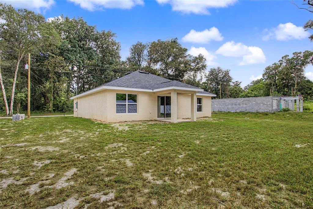 The exterior of a single-story stucco house with a hip roof and a grassy yard — 151 SE 81ST STREET, OCALA, FL