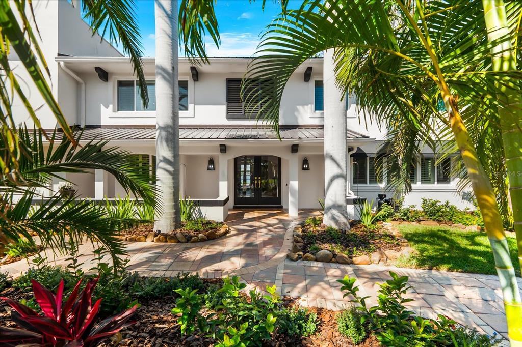 The exterior of a two-story white house features a paved walkway and palm trees — 16895 1ST STREET E, NORTH REDINGTON BEACH, FL