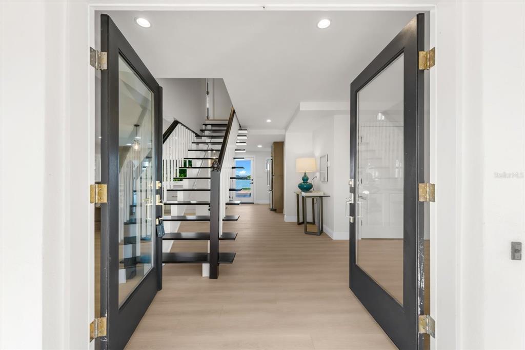An entryway with double glass doors opens to a staircase and a view of water — 16895 1ST STREET E, NORTH REDINGTON BEACH, FL