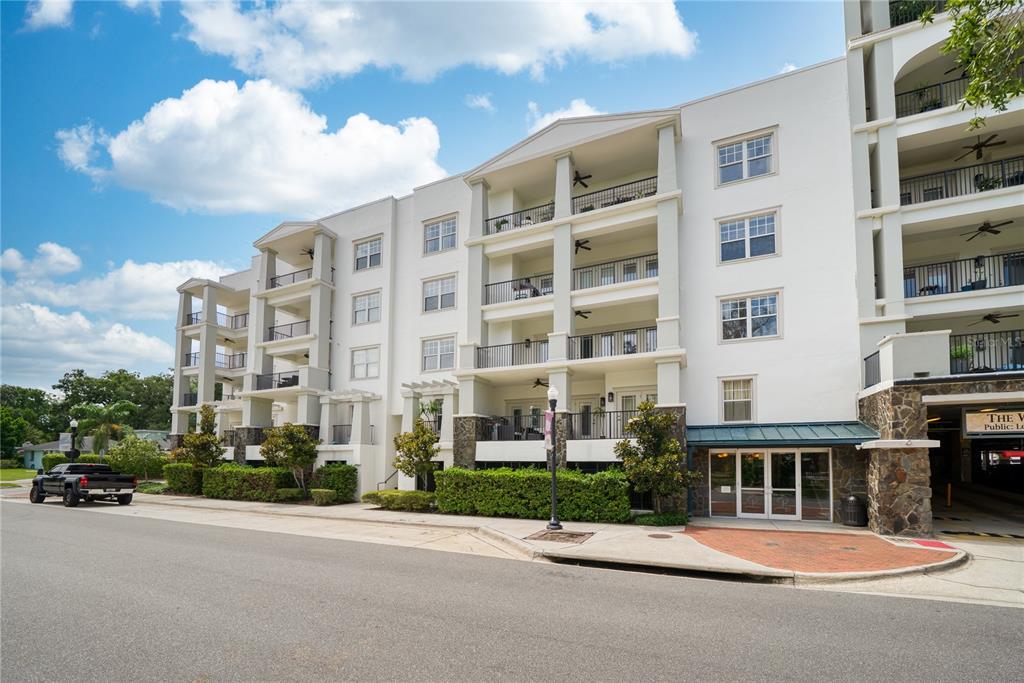 A multi-story apartment building with balconies, stone accents, and a ground-level parking entrance — 630 VASSAR STREET UNIT 2210, ORLANDO, FL