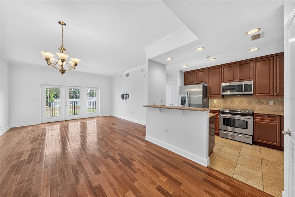 An open-concept living area with hardwood floors leads into a kitchen with wood cabinets — 630 VASSAR STREET UNIT 2210, ORLANDO, FL