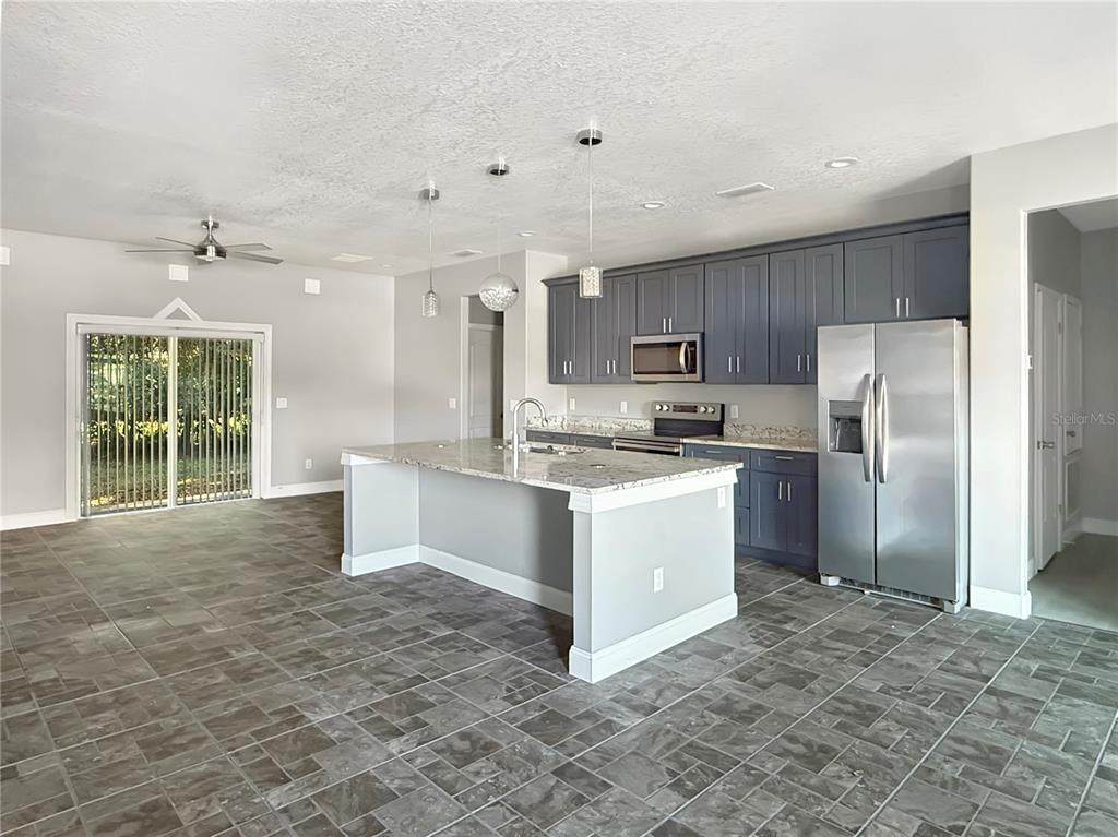 A kitchen with dark gray cabinets, granite countertops, a central island, and tiled flooring — 141 SCOTT DRIVE, SANFORD, FL