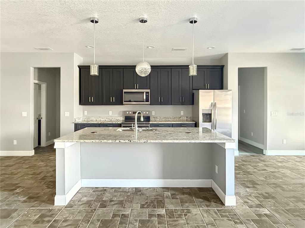 A kitchen features dark cabinets, stainless steel appliances, a granite island, and tiled flooring — 141 SCOTT DRIVE, SANFORD, FL