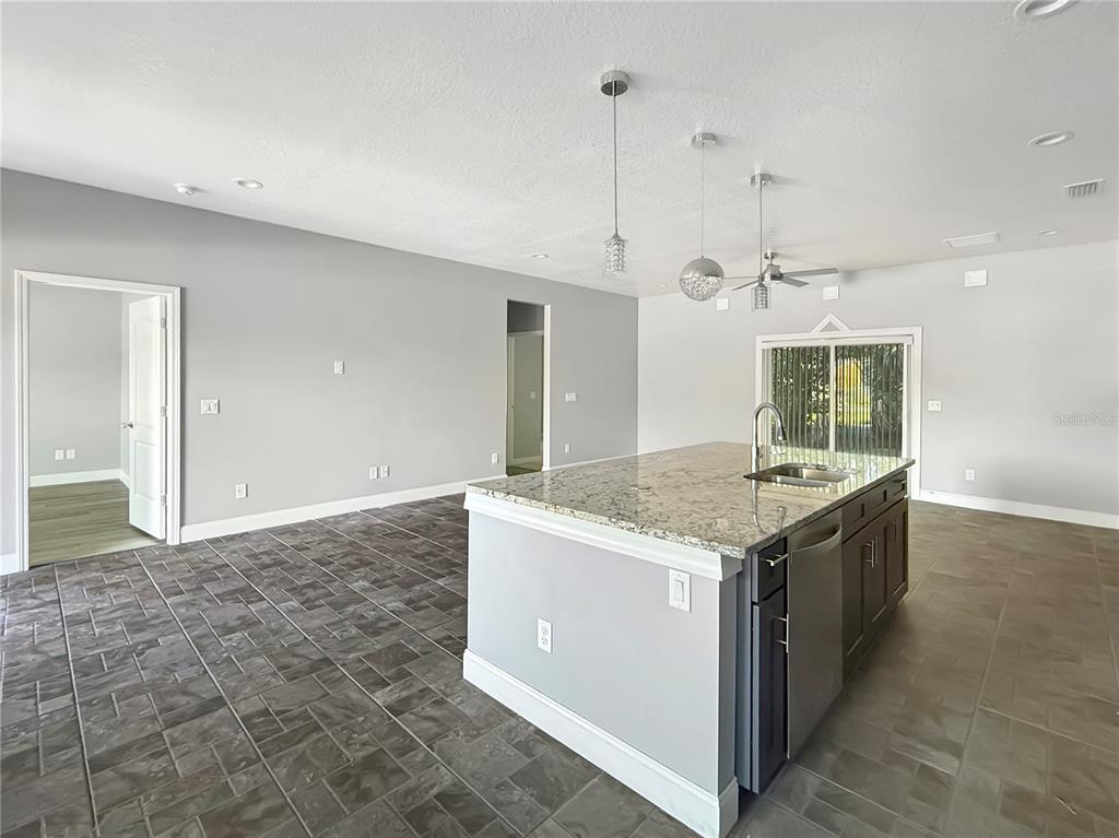 A kitchen island with granite countertops sits in a room with gray tile flooring — 141 SCOTT DRIVE, SANFORD, FL
