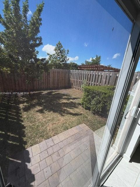 A view from a sliding glass door looking out onto a small fenced backyard patio — 12213 NW 23RD PL # 12213, Miami FL 33167, MIAMI, FL
