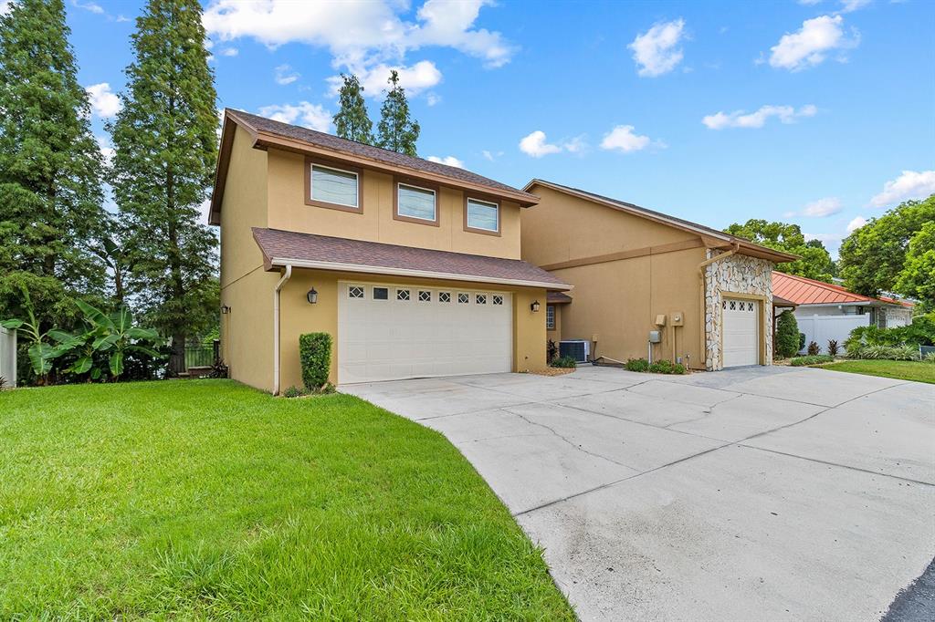 A two-story house with a tan exterior, two garage doors, and a concrete driveway — 614 MOUNTAIN LAKE PLACE, LAKELAND, FL