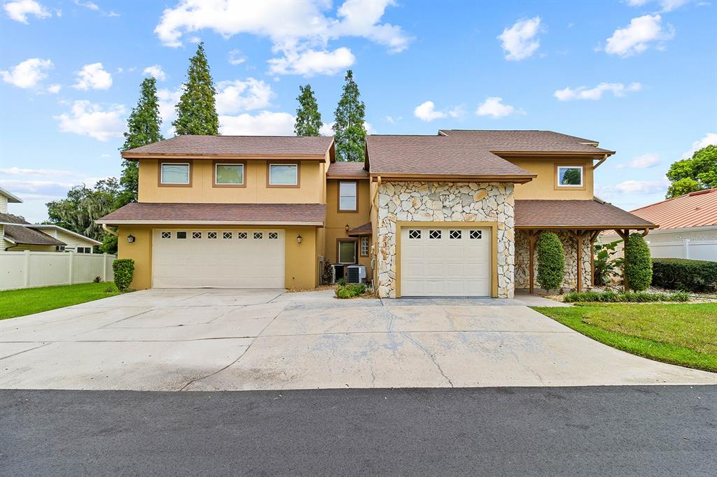 A two-story house with a tan exterior, stone facade, and two separate garage doors — 614 MOUNTAIN LAKE PLACE, LAKELAND, FL