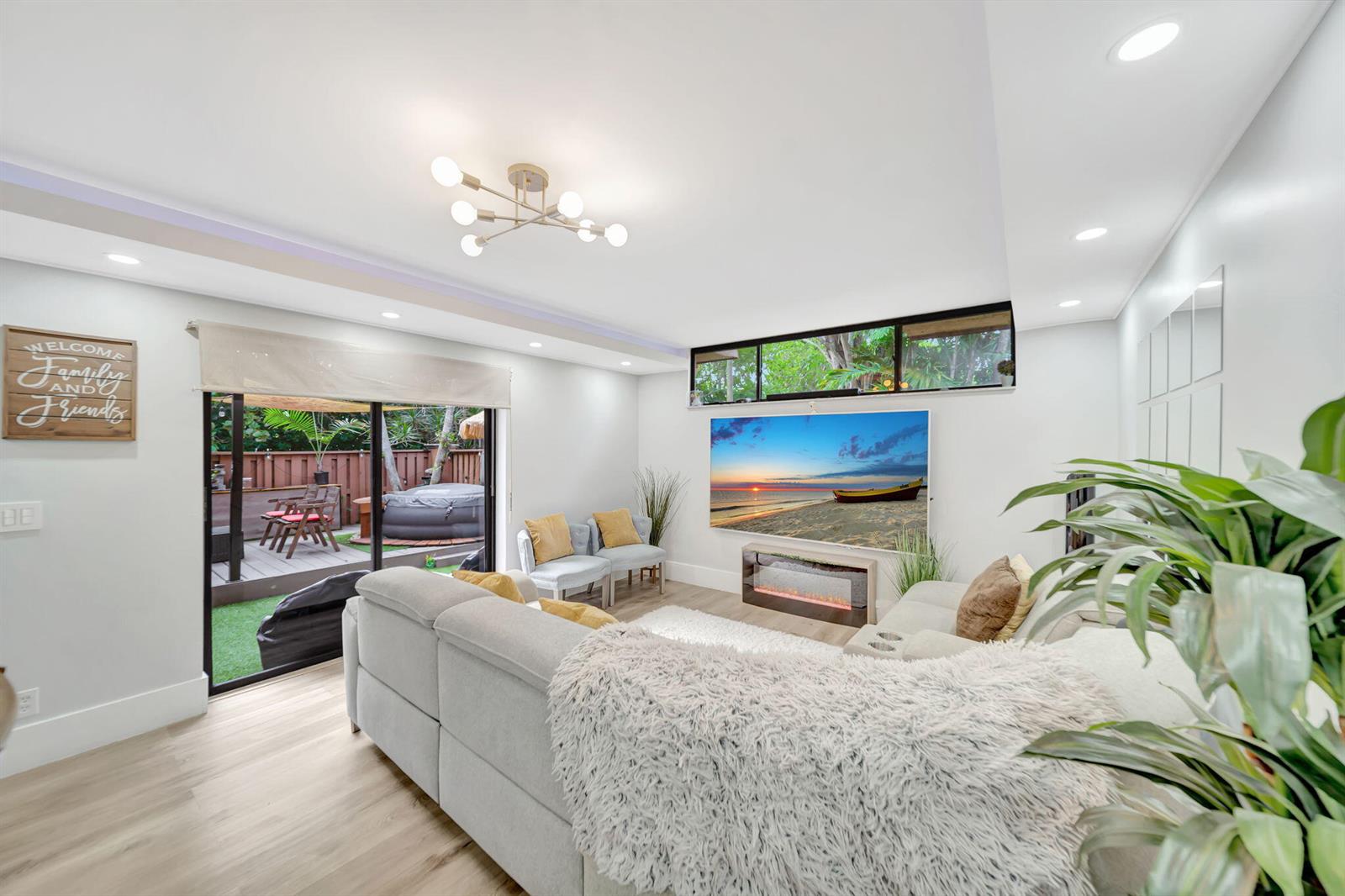 A living room features a sectional sofa, a wall-mounted television, and a sliding glass door — 8105 Severn Drive # C, Boca Raton FL 33433, BOCA RATON, FL