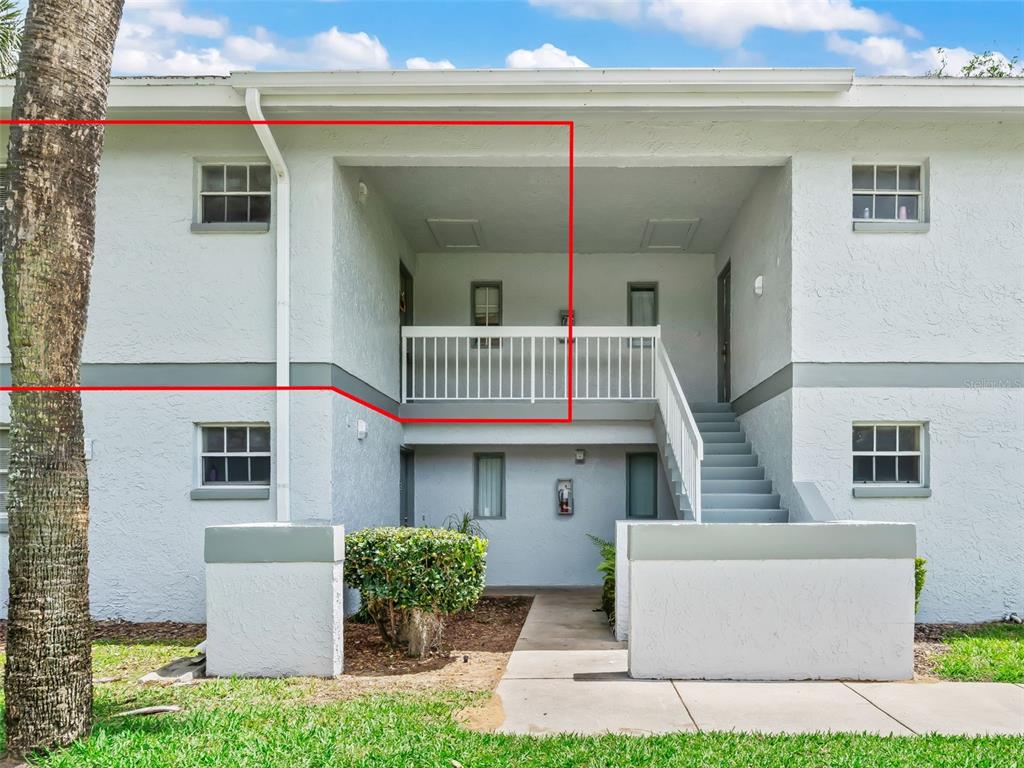 The exterior of a two-story apartment building features a second-floor balcony and outdoor staircase — 563 MIDWAY TRACK UNIT K203, OCALA, FL