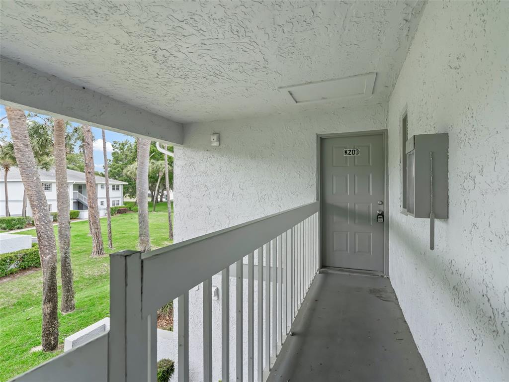 An exterior walkway leads to a gray apartment door labeled K203 with a metal railing — 563 MIDWAY TRACK UNIT K203, OCALA, FL