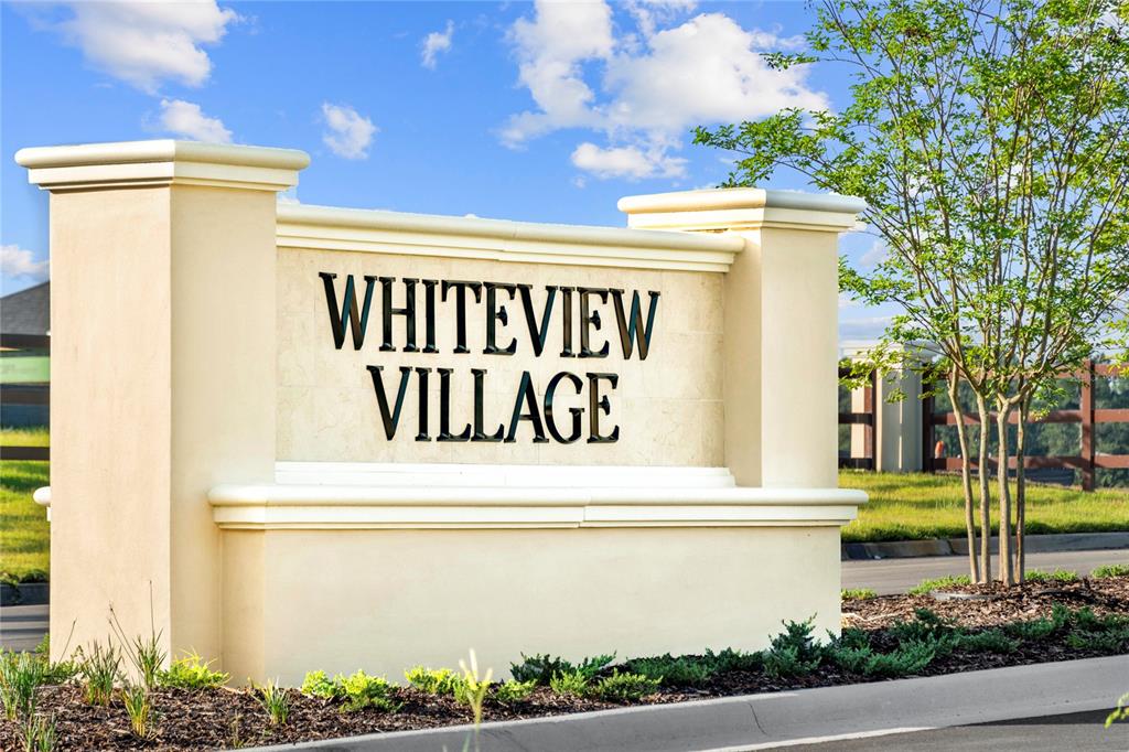 A beige monument sign with the text Whiteview Village stands outdoors under a blue sky — 124 WAVERLY LANE, PALM COAST, FL