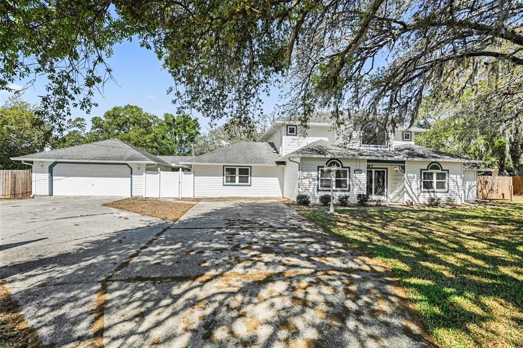 A two-story white house with a detached garage and a large concrete driveway — 18731 FIRETHORN DRIVE, SPRING HILL, FL