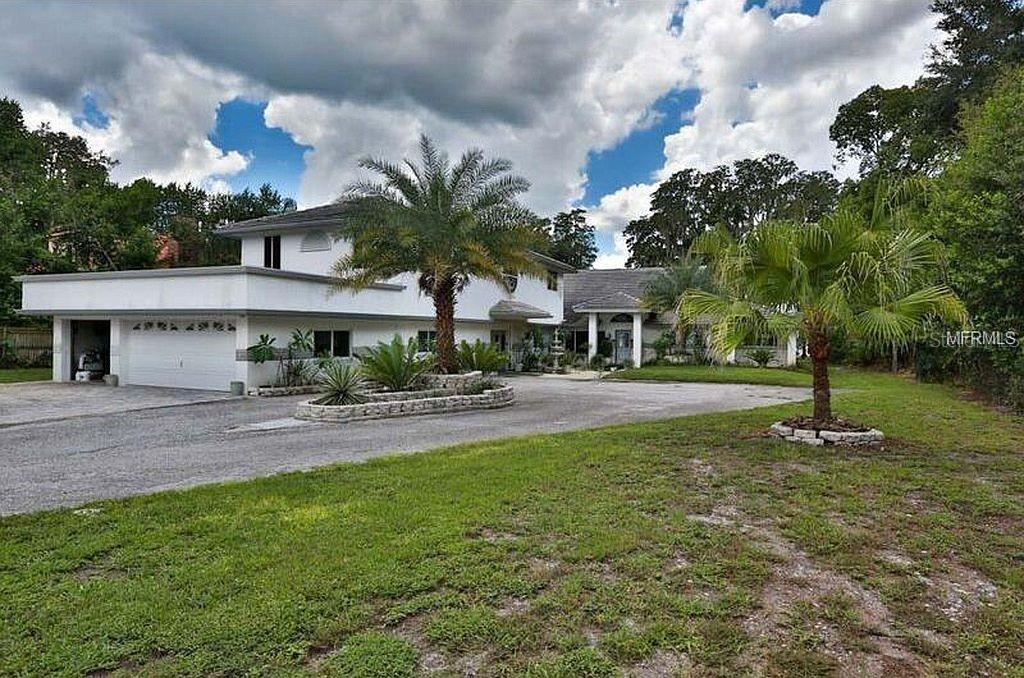 A two-story white house with a large driveway, palm trees, and a multi-car garage — 18618 WAYNE ROAD, ODESSA, FL