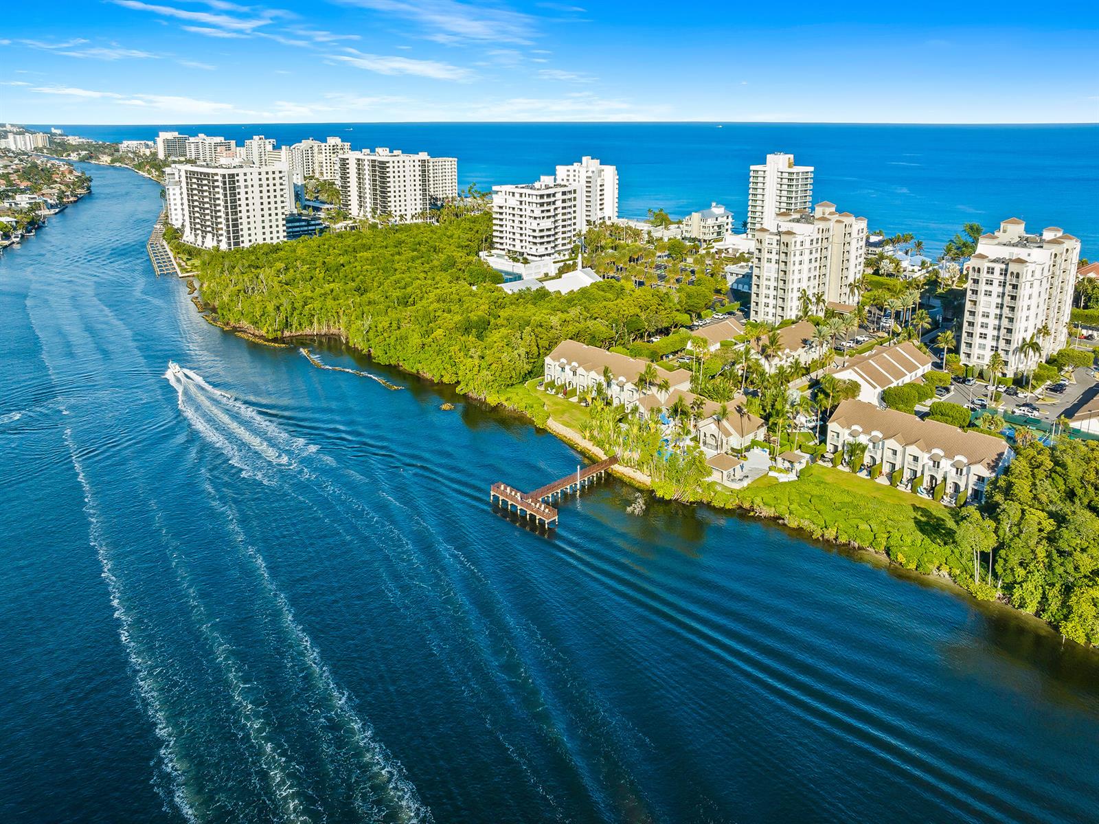 An aerial view shows a waterway with a boat alongside coastal buildings and lush vegetation — 3606 S Ocean Boulevard # 1004, Highland Beach FL 33487, HIGHLAND BEACH, FL