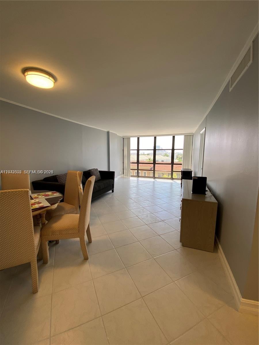 A dining area and living room feature light tile flooring, gray walls, and large windows — 2049 S Ocean Dr # 503, Hallandale Beach FL 33009, HALLANDALE BEACH, FL