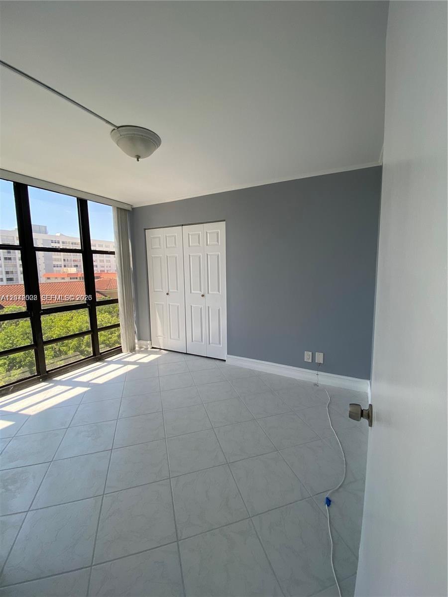 An empty bedroom features light gray walls, white tile flooring, a closet, and floor-to-ceiling windows — 2049 S Ocean Dr # 503, Hallandale Beach FL 33009, HALLANDALE BEACH, FL