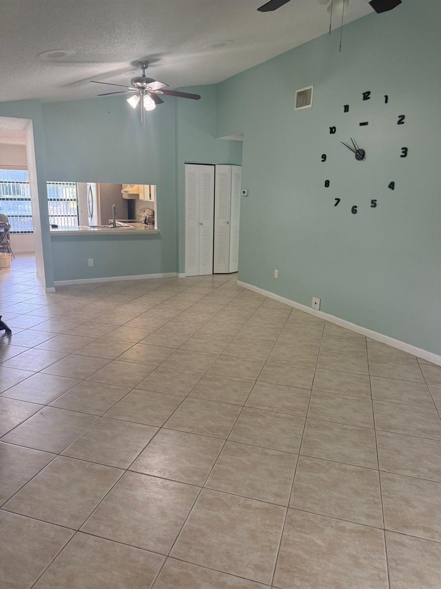 A spacious living area features light blue walls, beige tile flooring, and a large wall clock — 1463 Summit Run Circle, West Palm Beach FL 33415, WEST PALM BEACH, FL