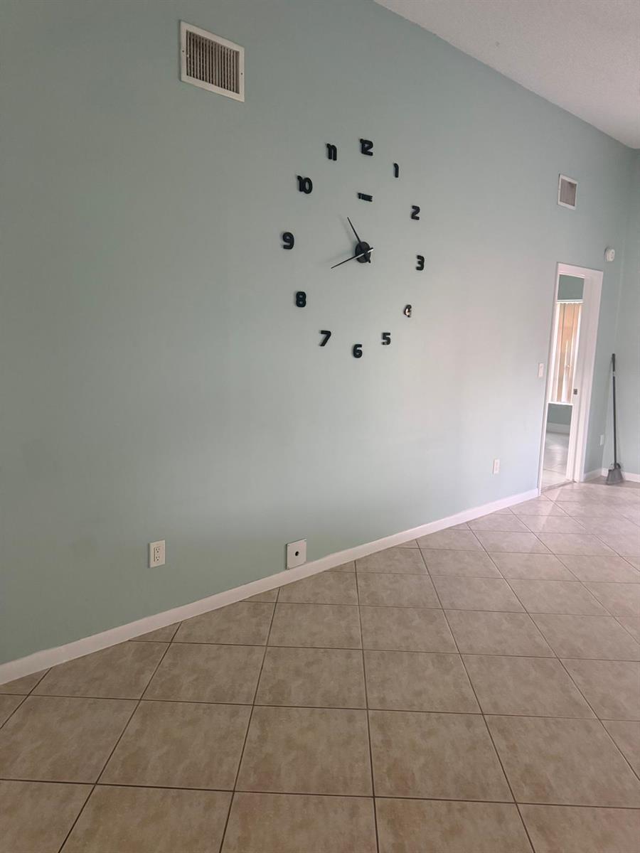 A room with light blue walls, tile flooring, and a large wall-mounted clock — 1463 Summit Run Circle, West Palm Beach FL 33415, WEST PALM BEACH, FL